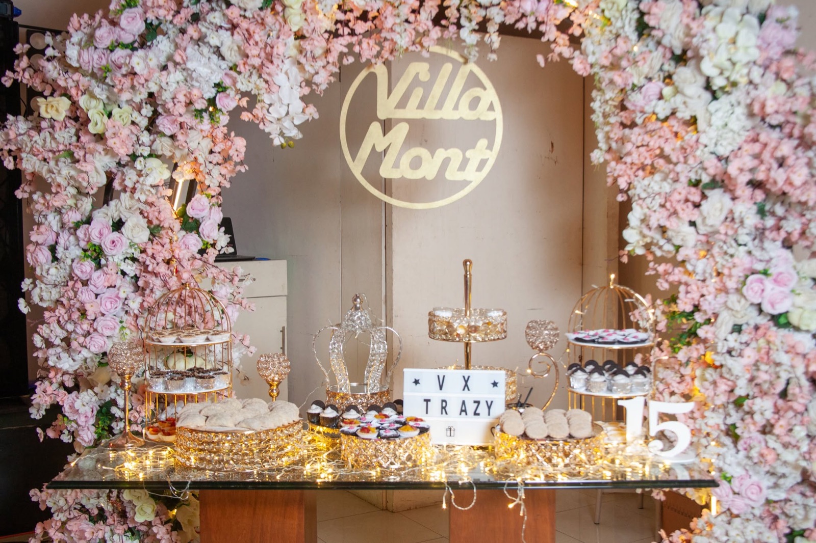 Mesa de postres con arco floral y logotipo de VillaMont