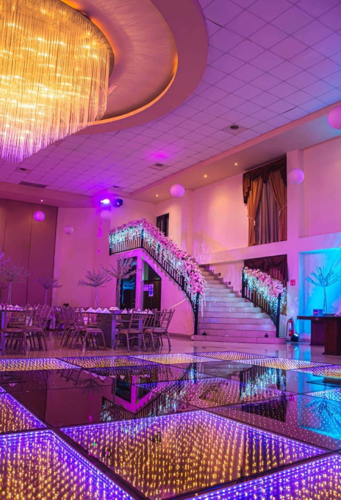 Salón VillaMont con pista iluminada, candelabro y escalera decorada con flores