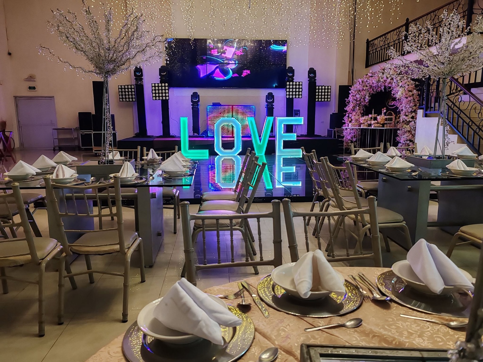 Mesas del salón VillaMont con letras LOVE iluminadas y decoración floral